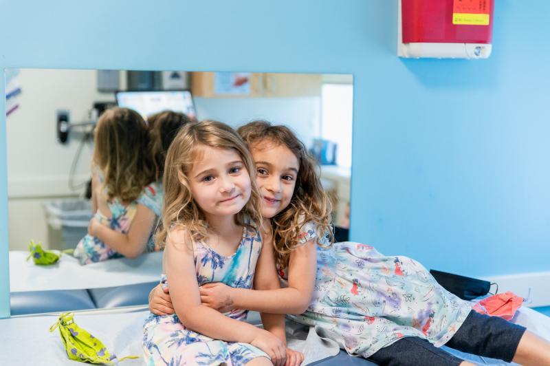 girls hugging each other on an exam table