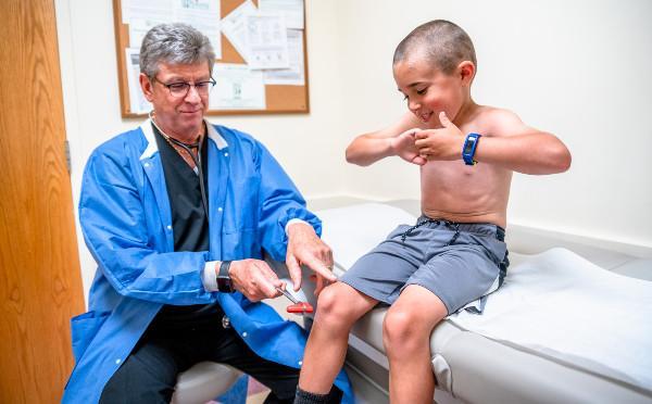 a boy on an exam table with a doctor checking his knee