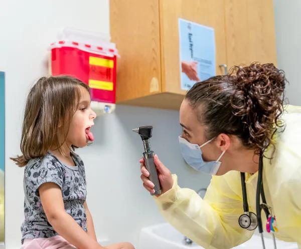 a doctor examining a girl's tonsils