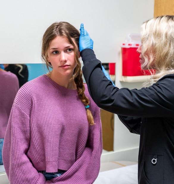 a pretty teenage girl getting her ear examined