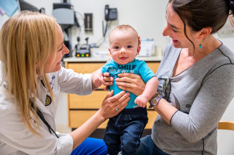 an infant in between his mom and a pediatrician