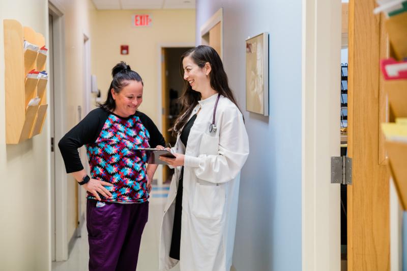 a physician and a nurse talking in a hallway